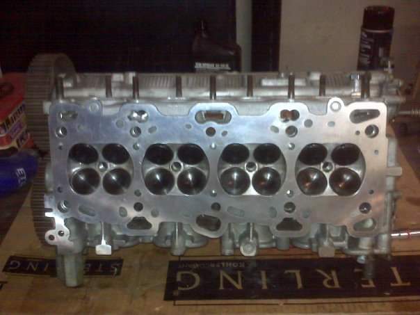 Cleaned Mitsubishi 4G63 cylinder head on a workbench, combustion chambers facing up