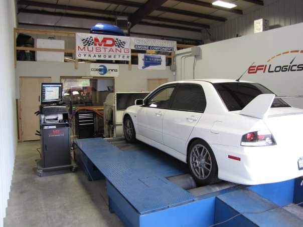 White Mitsubishi Lancer Evolution strapped onto a blue Mustang dynamometer in a tuning shop