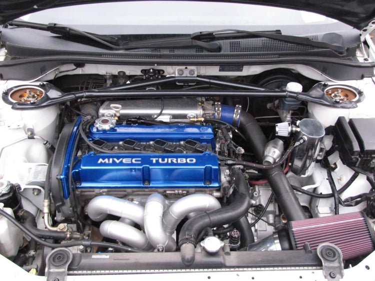 Tuned Mitsubishi Lancer Evolution engine bay with a blue MIVEC Turbo valve cover, polished intake piping and a cone air filter